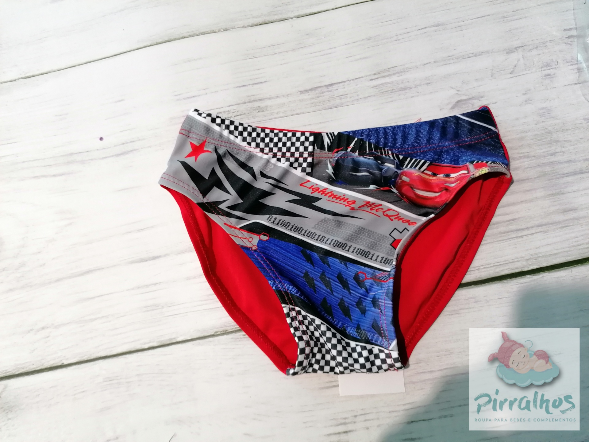 Cuecas de criança com estampas do filme Cars, em tecido colorido, sobre fundo de madeira clara