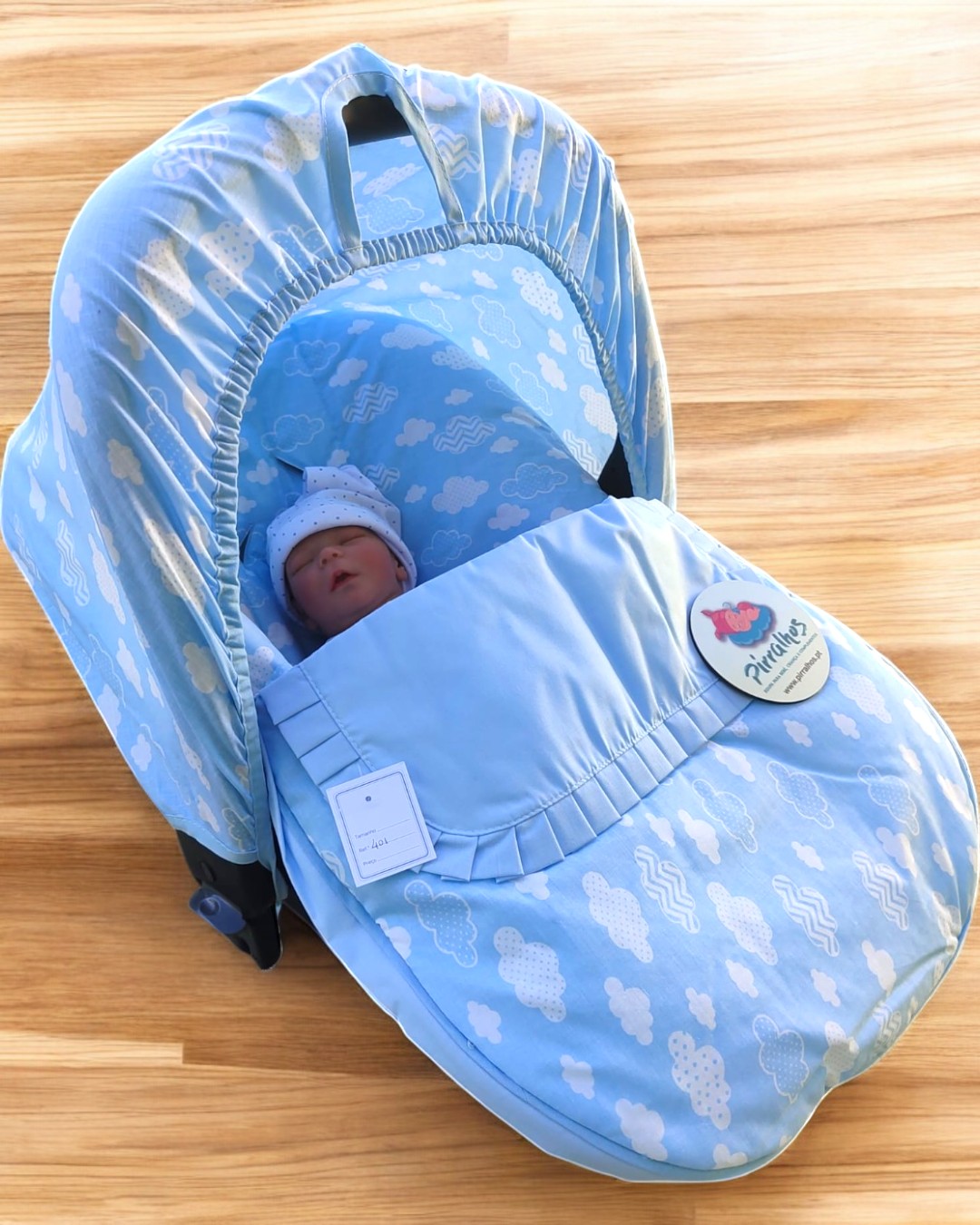 Cadeira de bebé azul com padrão de nuvens e boneco vestido de azul.