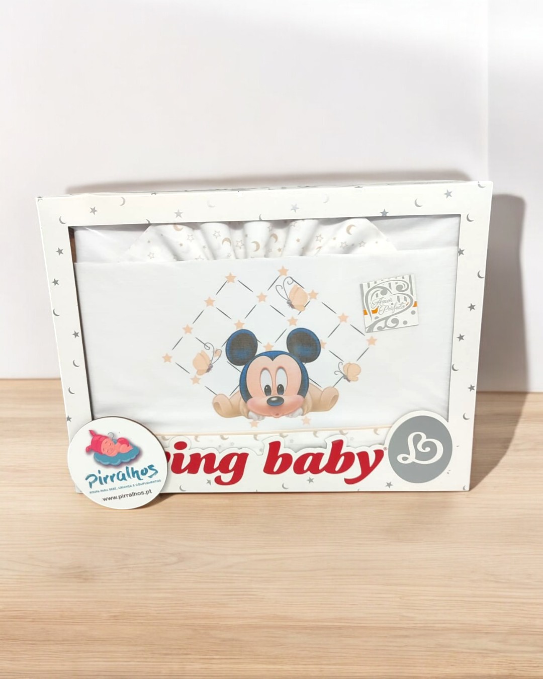 Caixa branca de roupa de bebé com desenho do Mickey Mouse e decoração de estrelas douradas