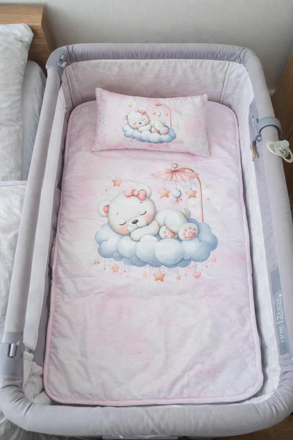 Berço com roupa de cama rosa e estampa de ursos em nuvens