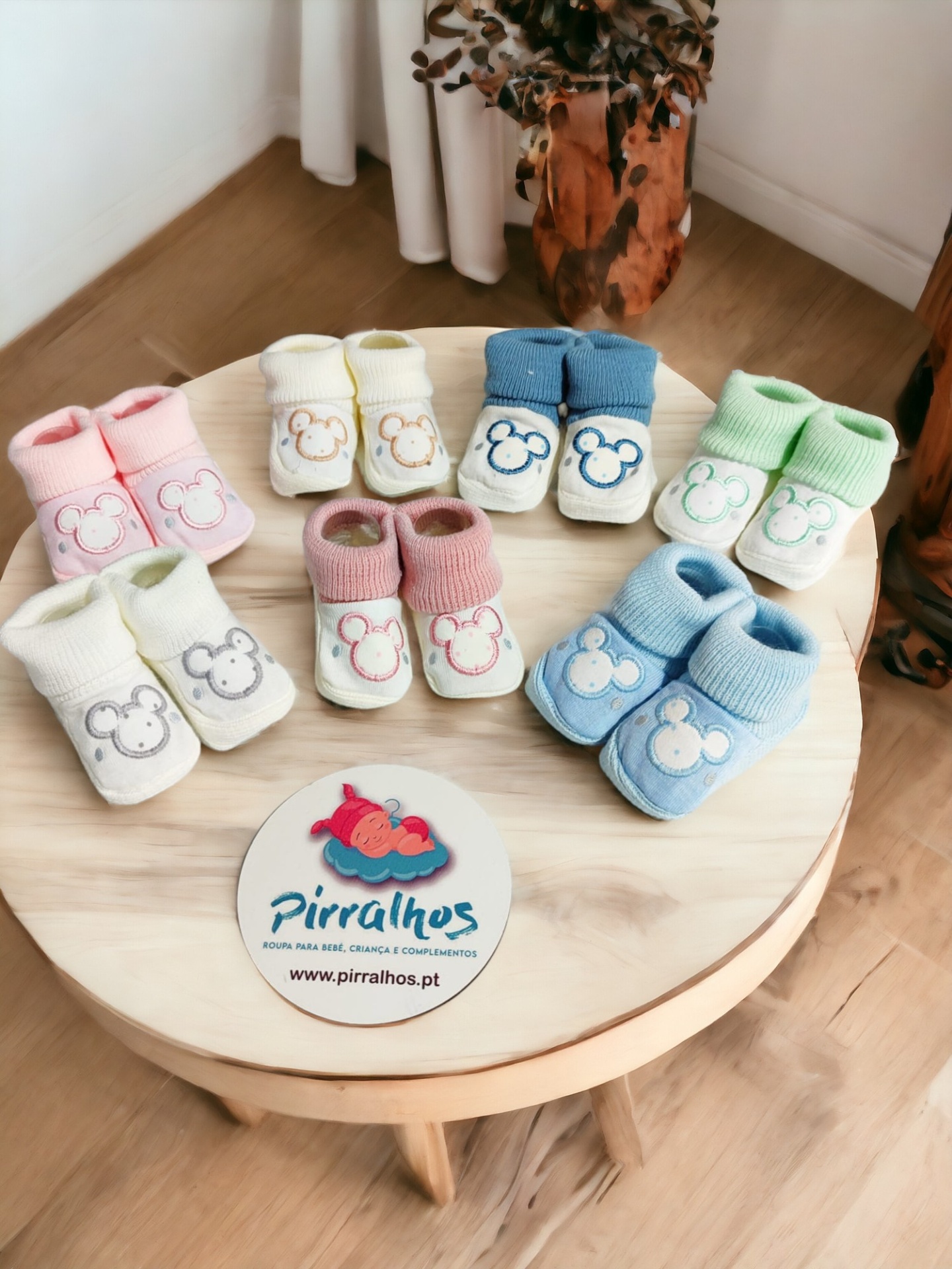 Meias de bebé coloridas com padrão de rato sobre mesa de madeira redonda
