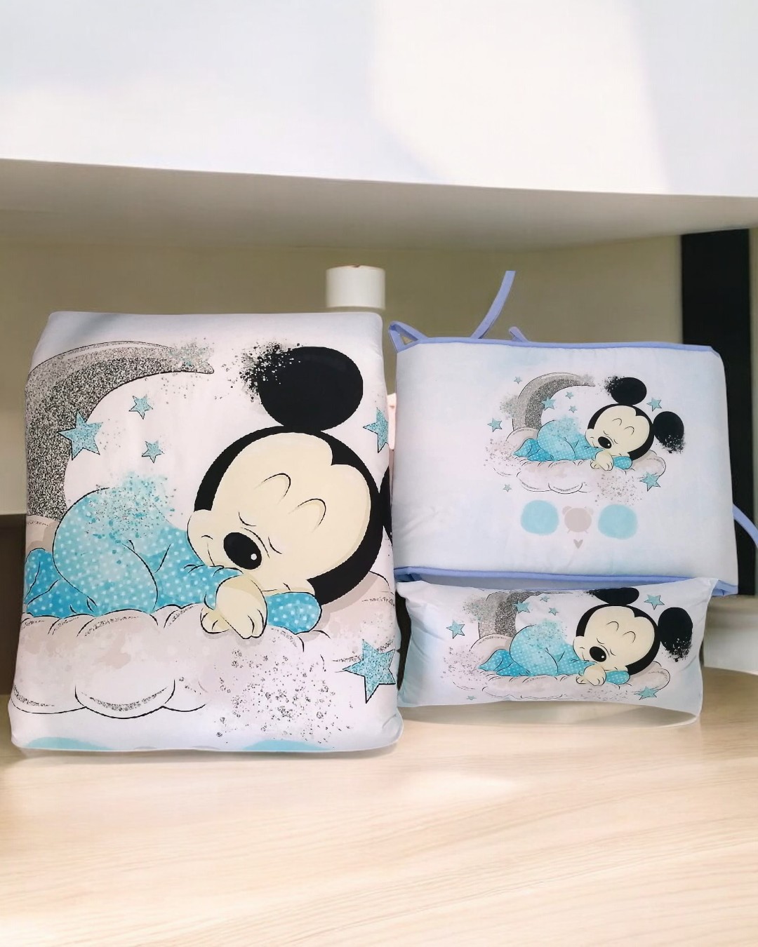 Itens têxteis para bebé com estampa do Mickey Mouse dormindo em fundo branco com estrelas e nuvens