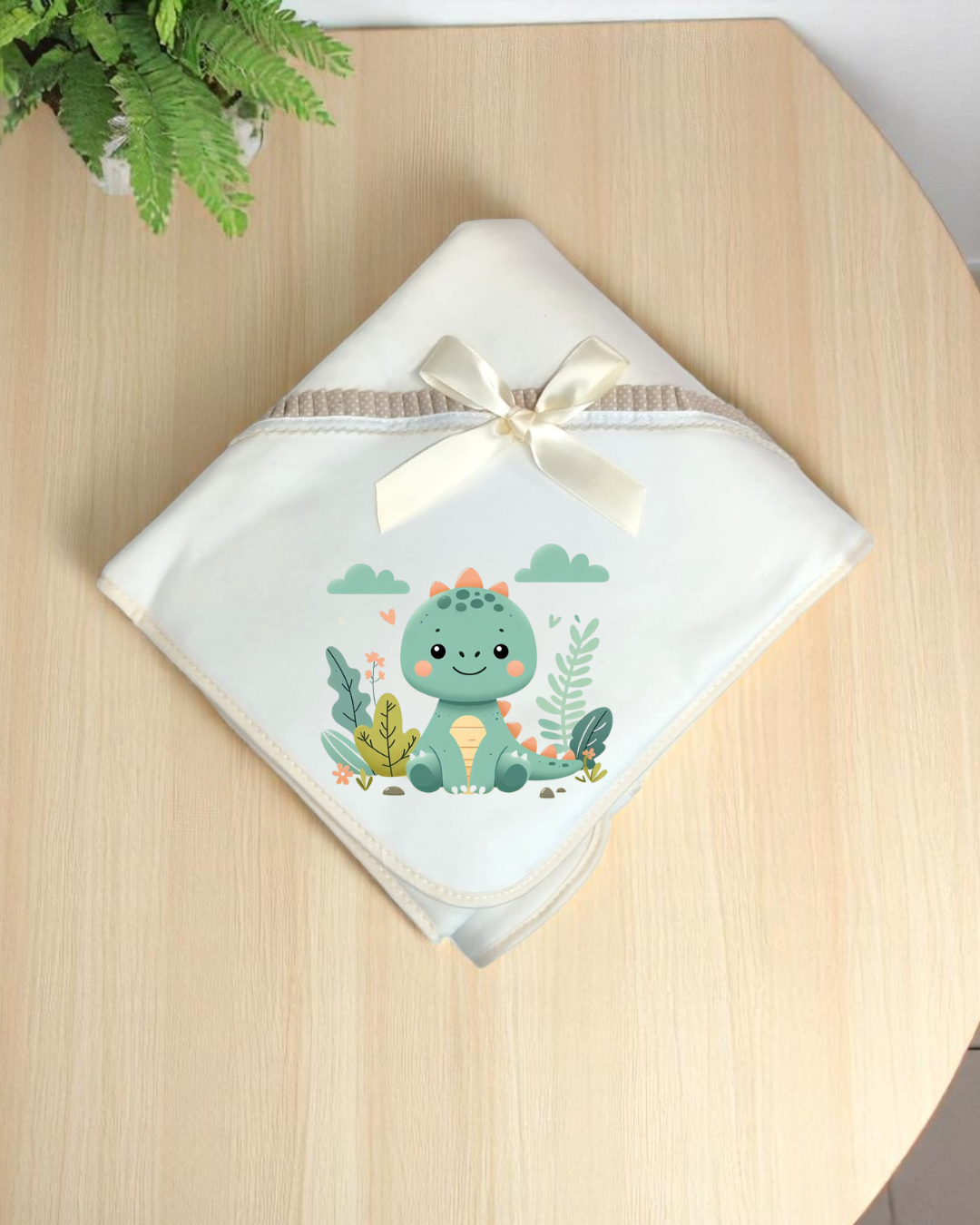 Manta branca para bebé com desenho de dinossauro verde e fita de cetim creme
