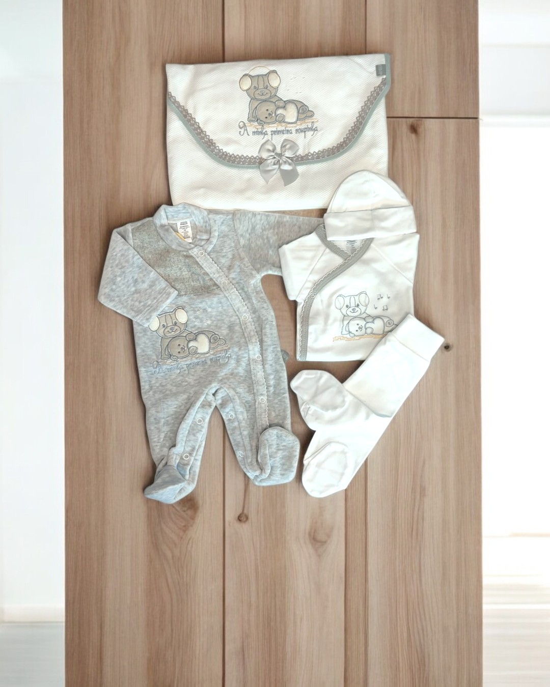 Conjunto de roupa de bebé com pijama cinza e acessórios brancos decorados com ratinho