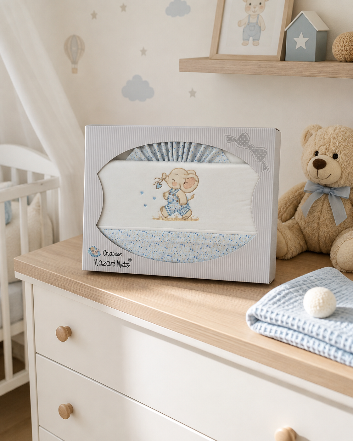 Conjunto de roupa de cama para bebé em embalagem com elefante bordado azul.