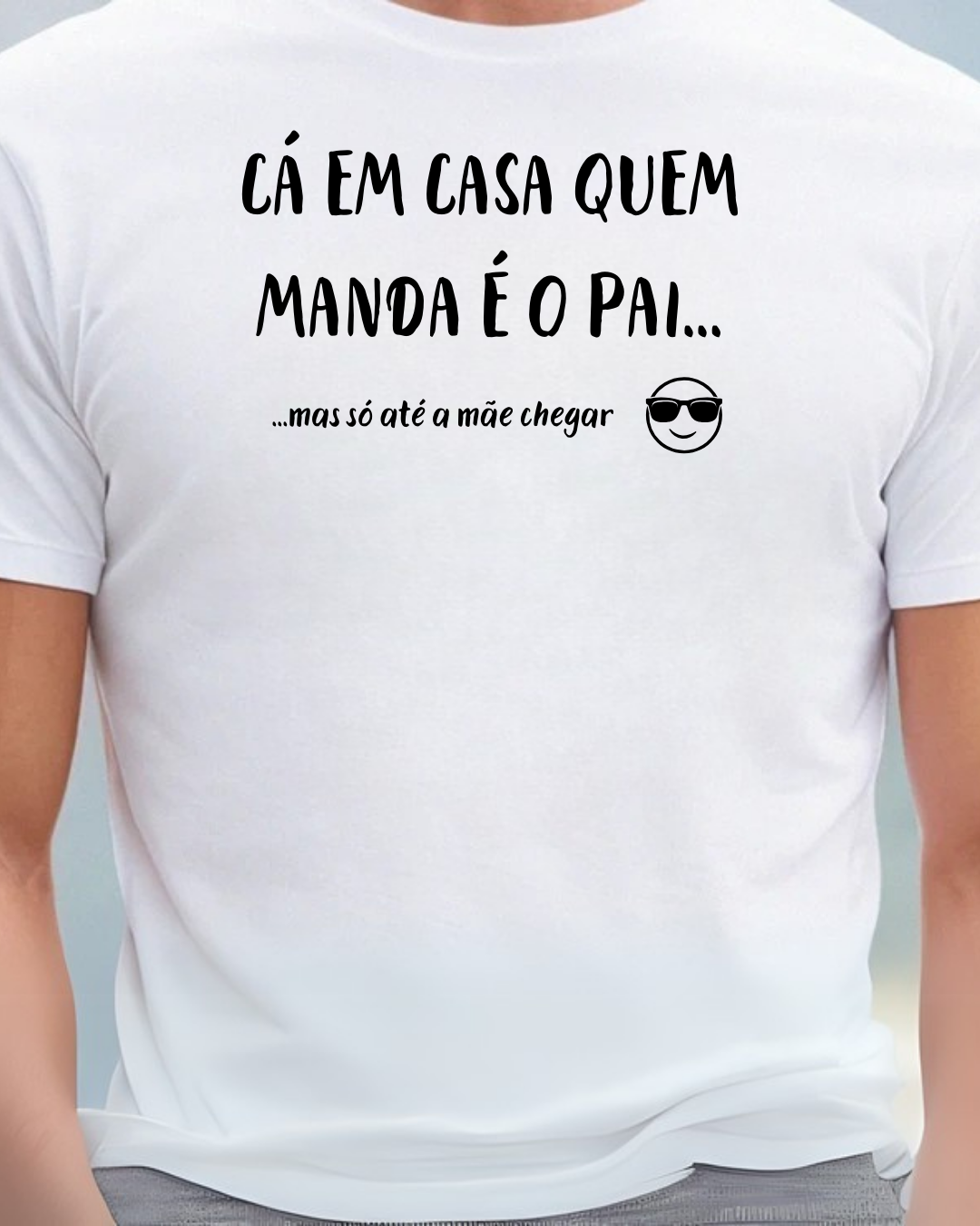 T-shirt branca com texto humorístico em preto e emoji, usada por uma pessoa.
