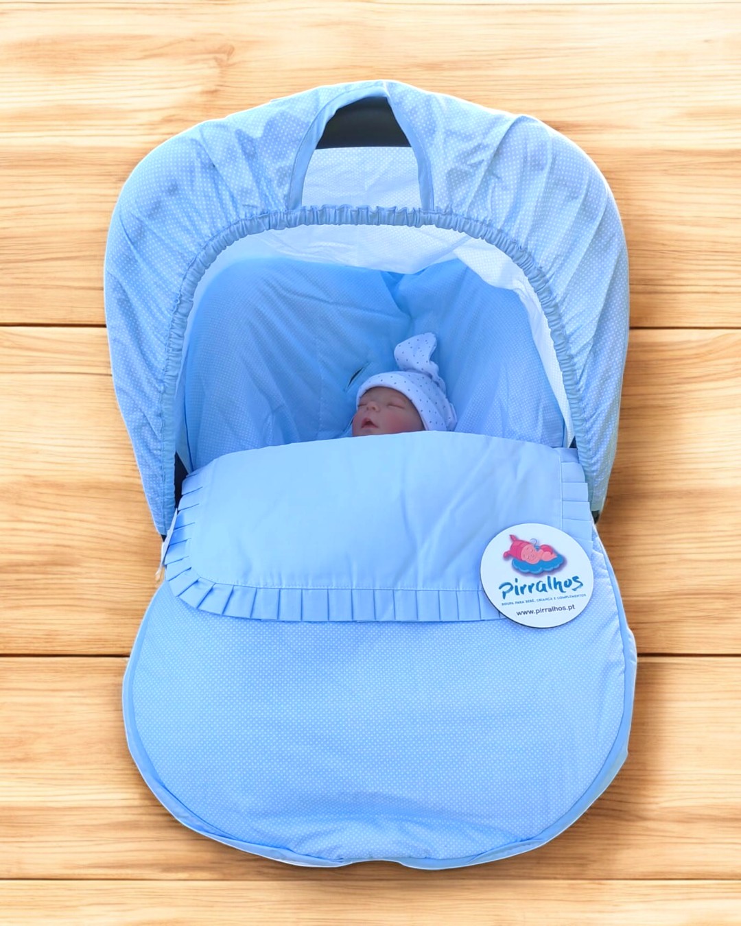 Berço portátil azul claro com boneco de bebé e botão Pirralhos