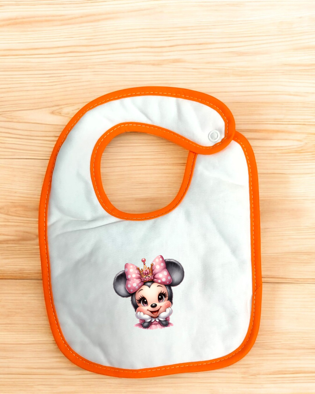 Babete para bebé branco com borda laranja e personagem de rato com coroa e laço rosa.
