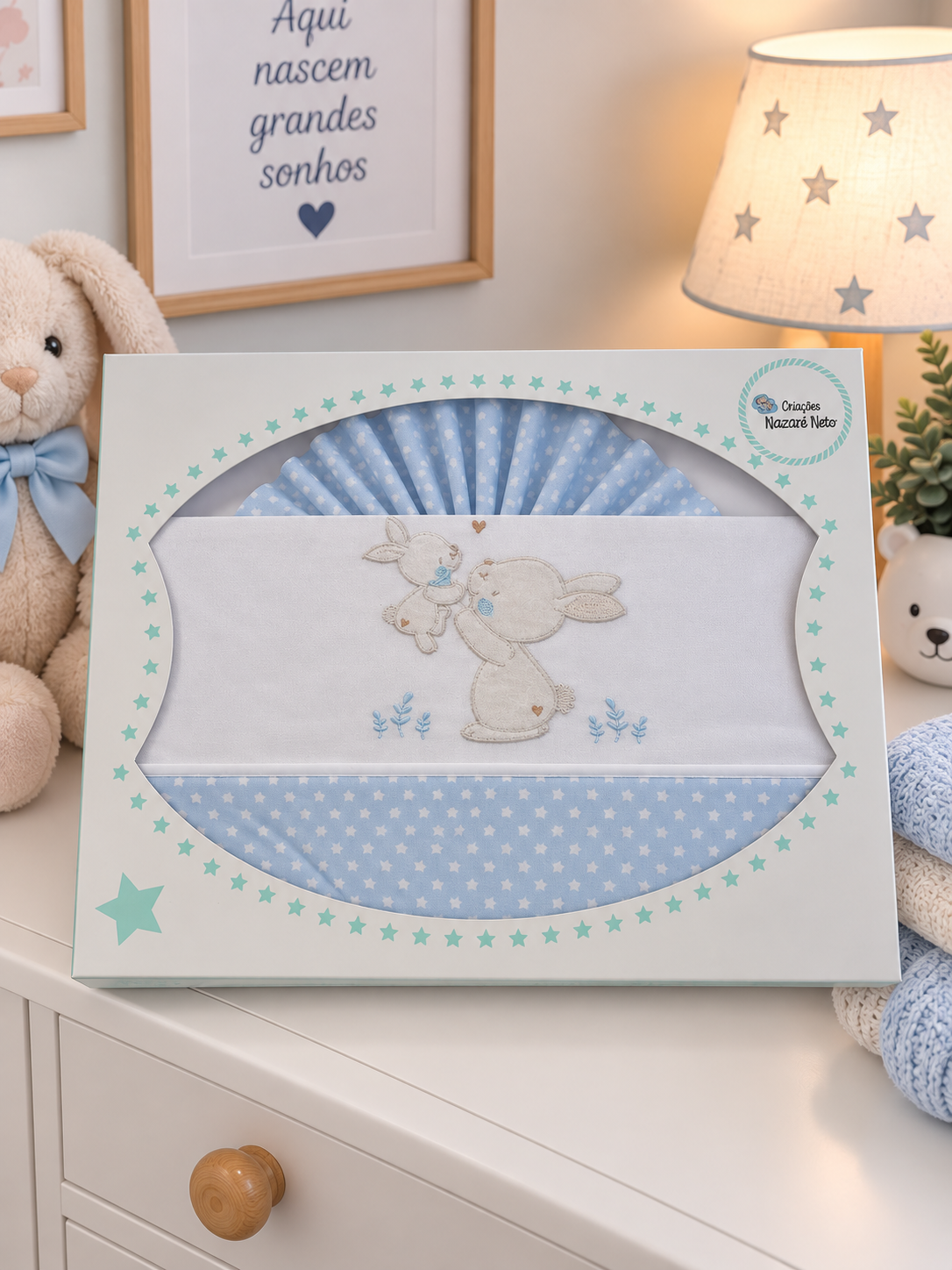 Lençóis de berço azuis com estrelas e bordado de coelhos na embalagem decorada com estrelas.