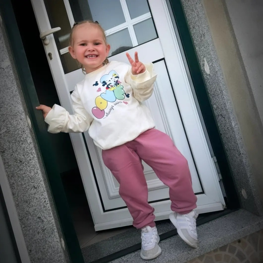 Menina sorridente com roupa casual colorida na soleira de uma porta