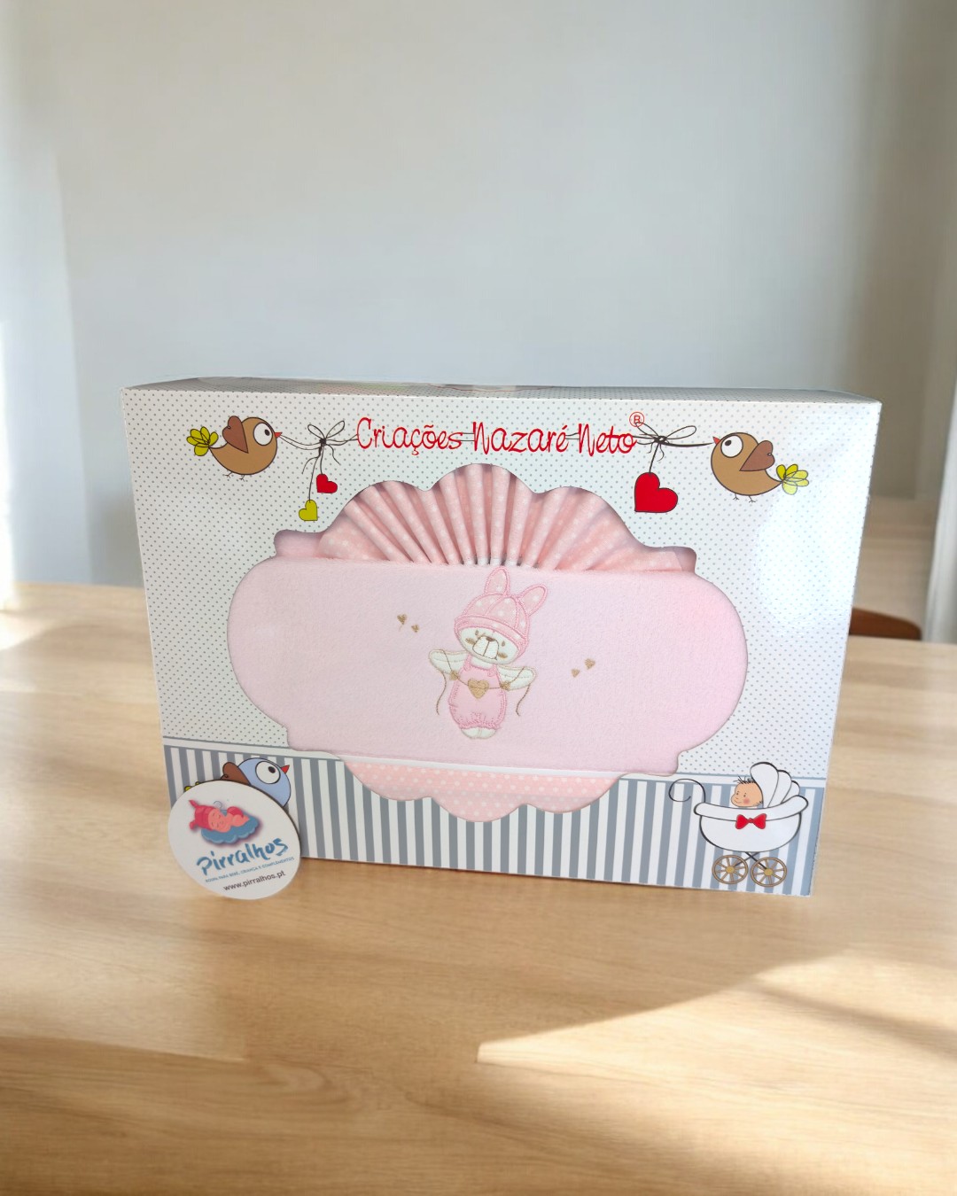 Caixa rosa para bebé com bordado de coelho e desenhos de pássaros e corações na embalagem.