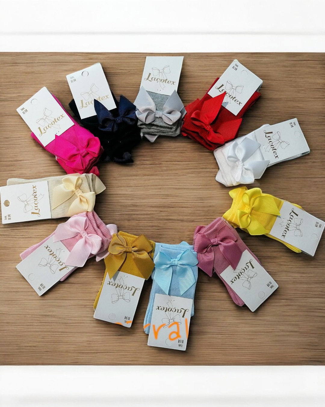 Doze pares de meias infantis coloridas com laços em círculo sobre madeira