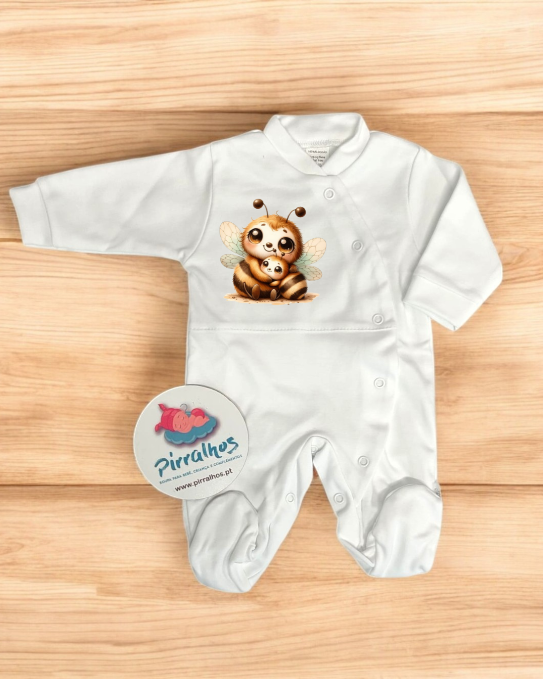 Macacão de bebé branco com estampado de abelhas em superfície de madeira