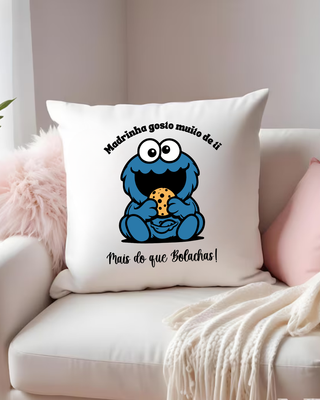 Almofada branca com desenho colorido e texto preto num sofá branco com manta creme