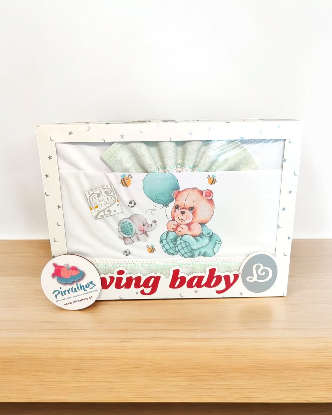 Jogo de cama para bebé com design de ursinho e balão em embalagem branca com estrelas.