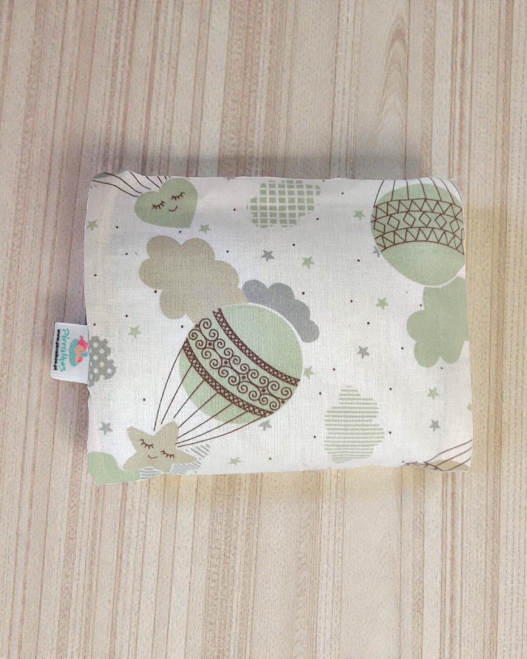 Almofada com padrão de balões e estrelas verdes e cinza sobre fundo branco