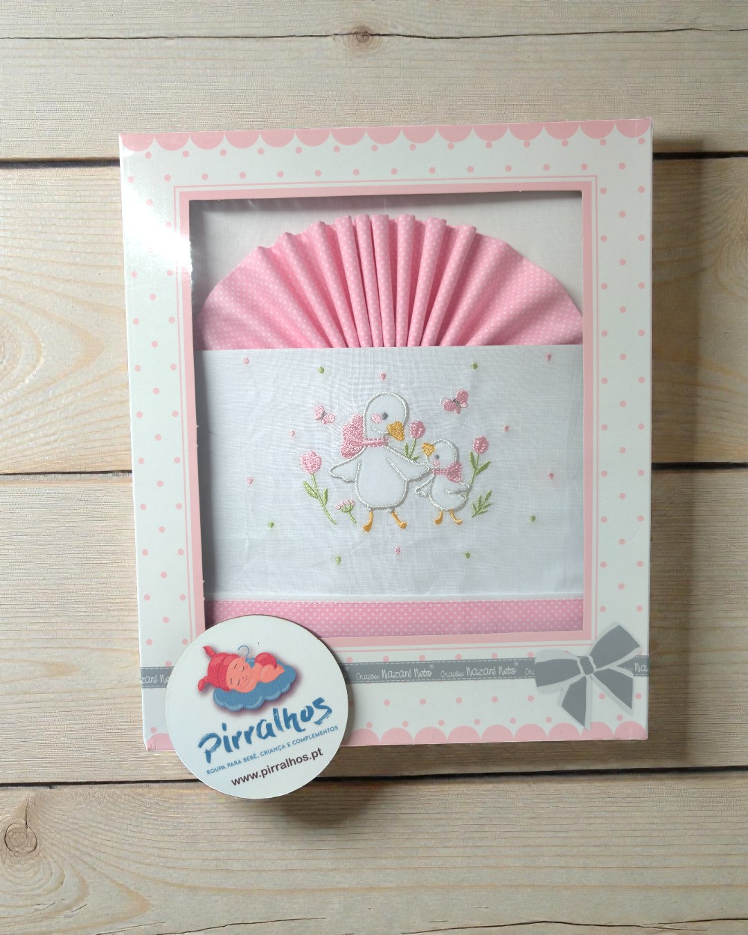 Conjunto para bebé em tecido branco e rosa com bordado de patinhos e embalagem decorativa.