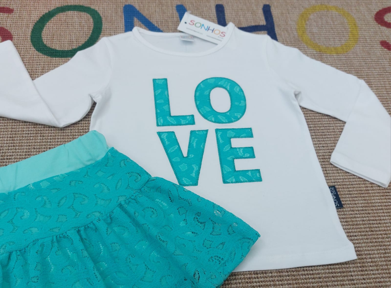 Conjunto de roupa infantil branca e turquesa com padrão de pequenos círculos