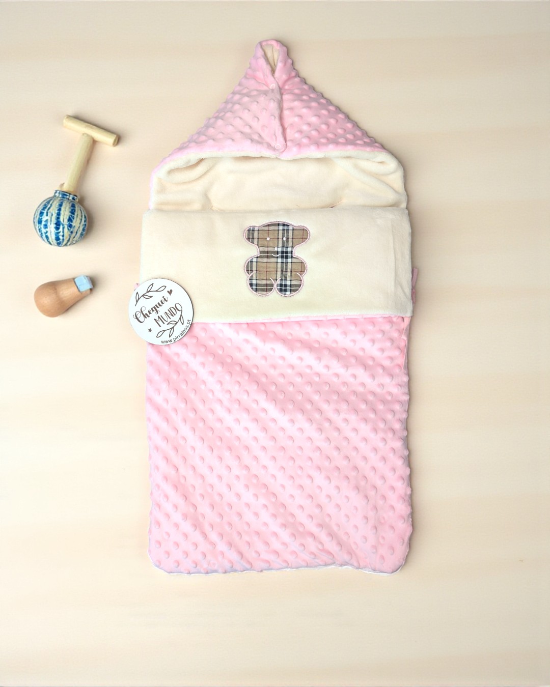 Saco de bebé cor-de-rosa com padrão bolinhas e ursinho xadrez, mais brinquedos em madeira