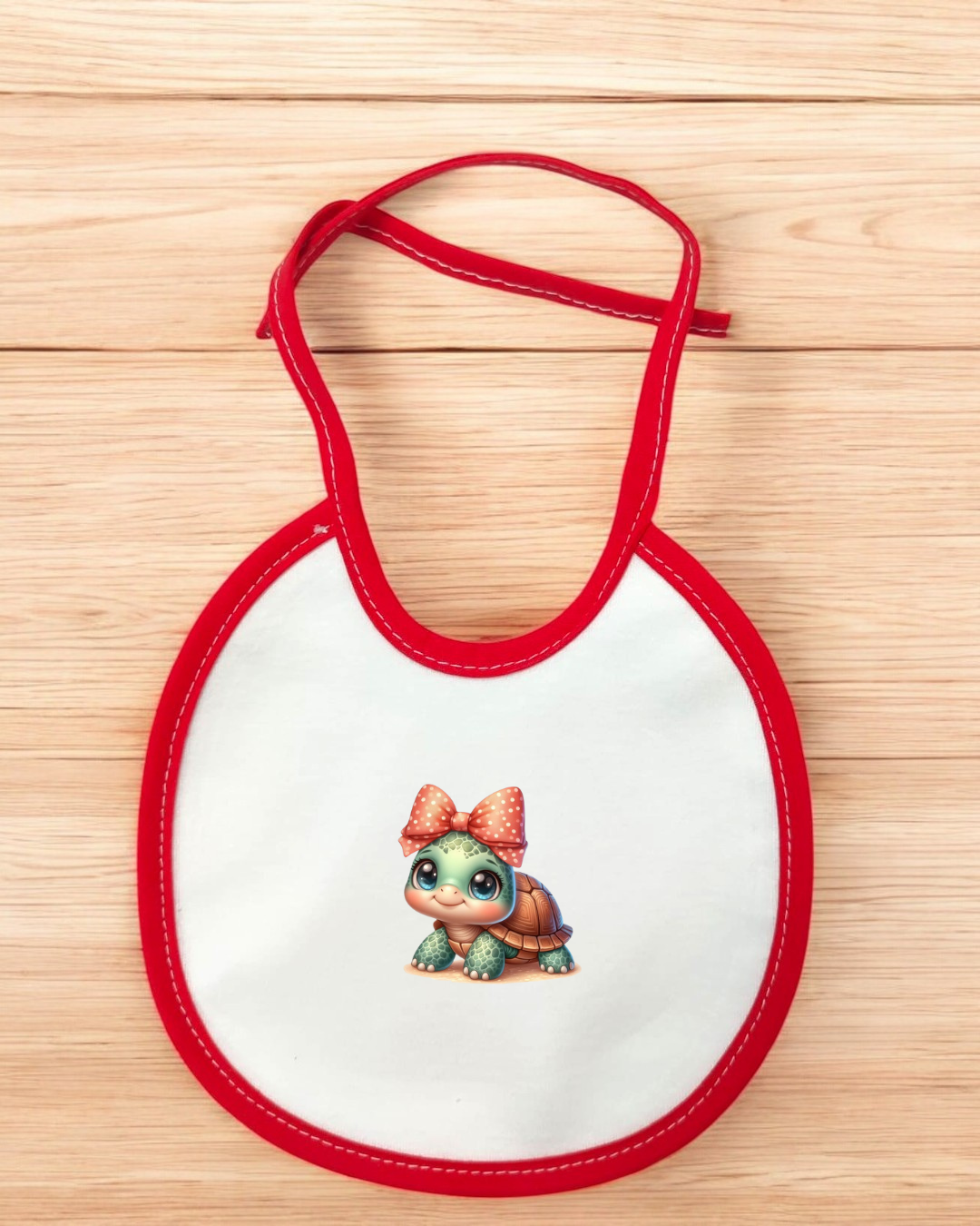 Babete branco com bordas vermelhas e estampado com tartaruga e laço rosa