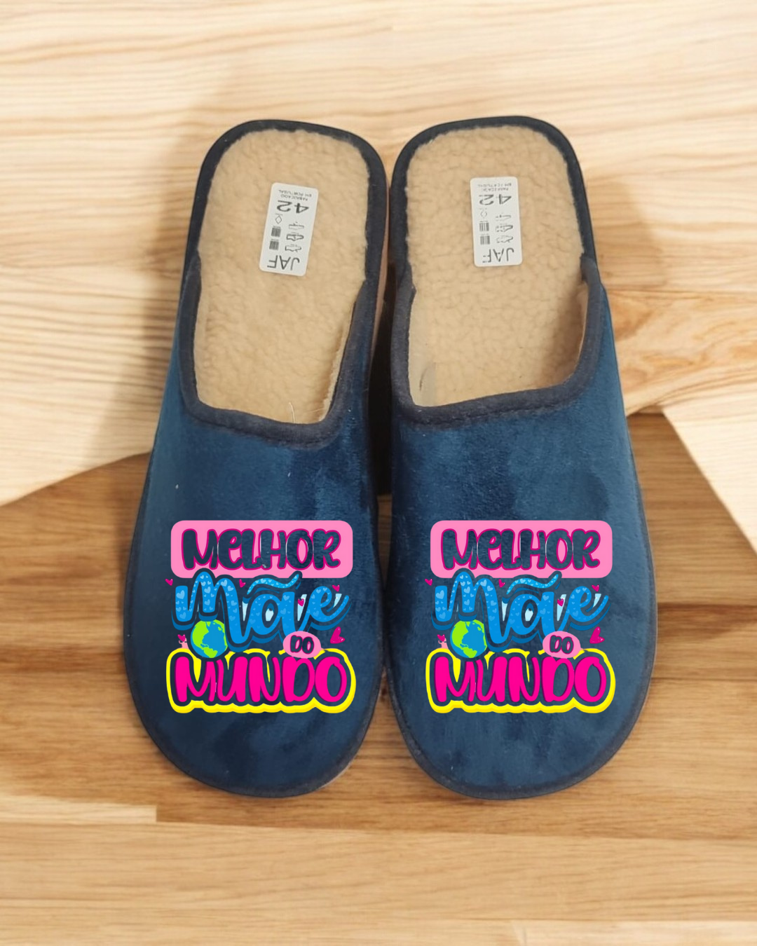 Chinelos azuis com frase MELHOR MÃE DO MUNDO em fundo madeira