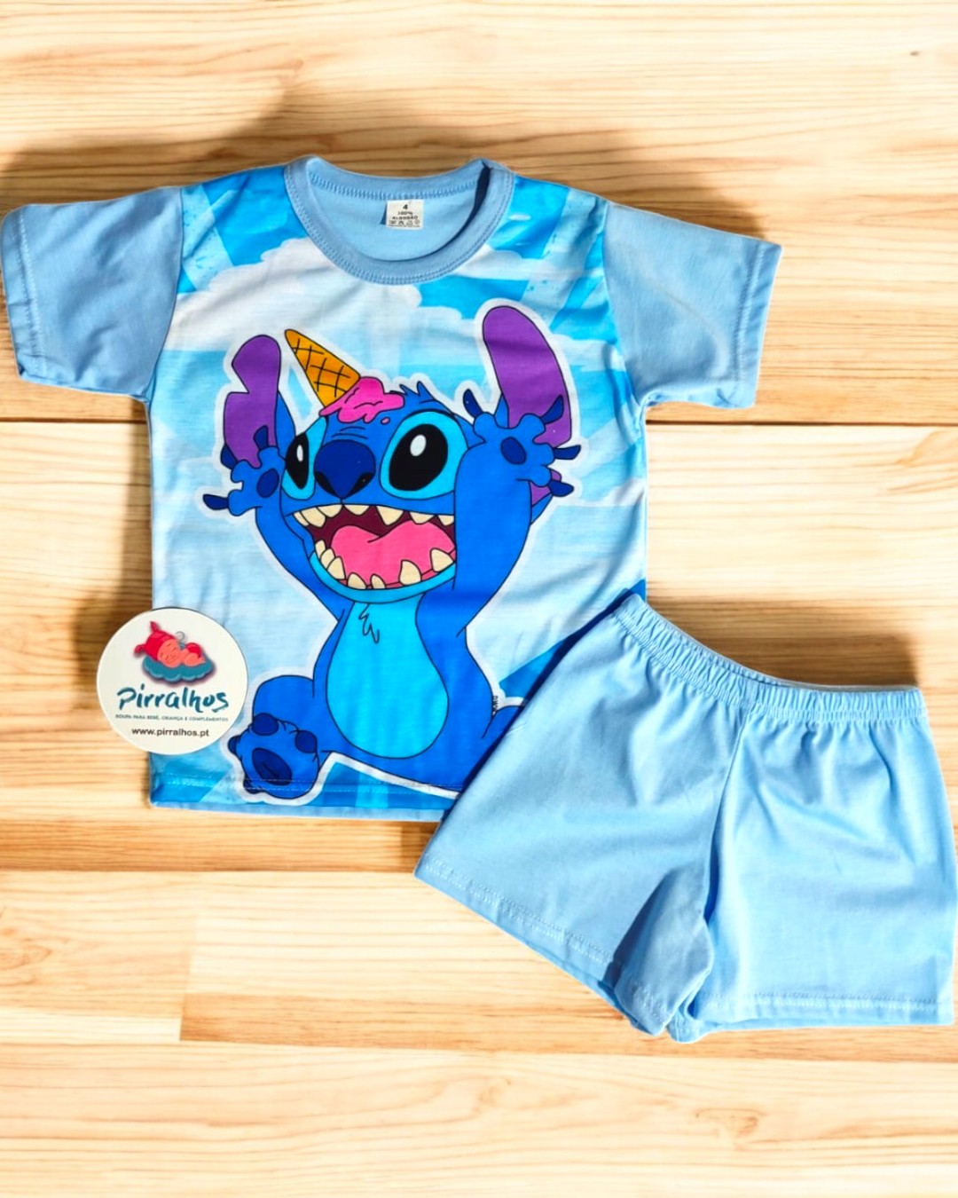 Conjunto infantil azul com personagem Stitch e calções lisos em fundo de madeira