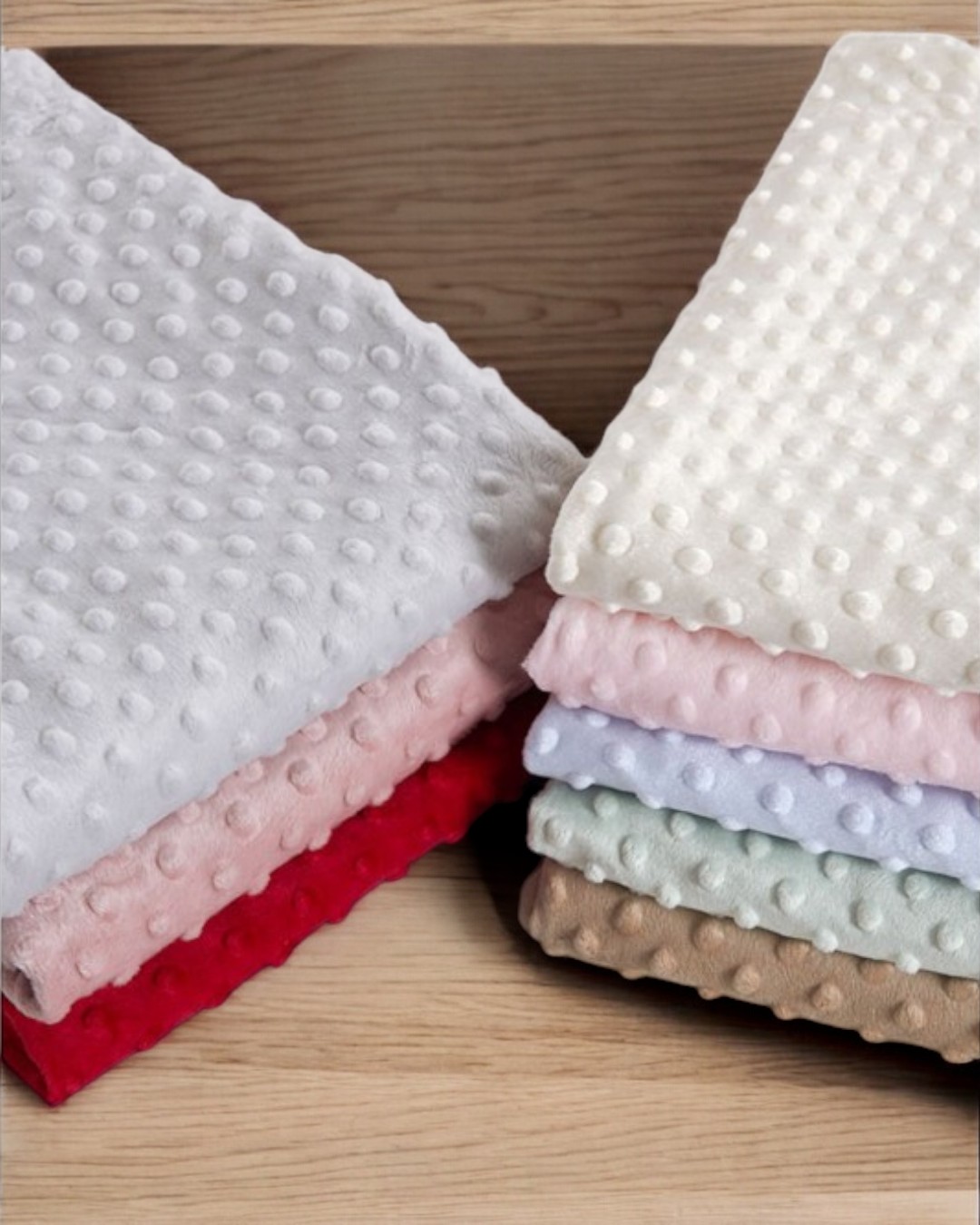 Tecidos com padrão de bolinhas em relevo em várias cores sobre madeira clara