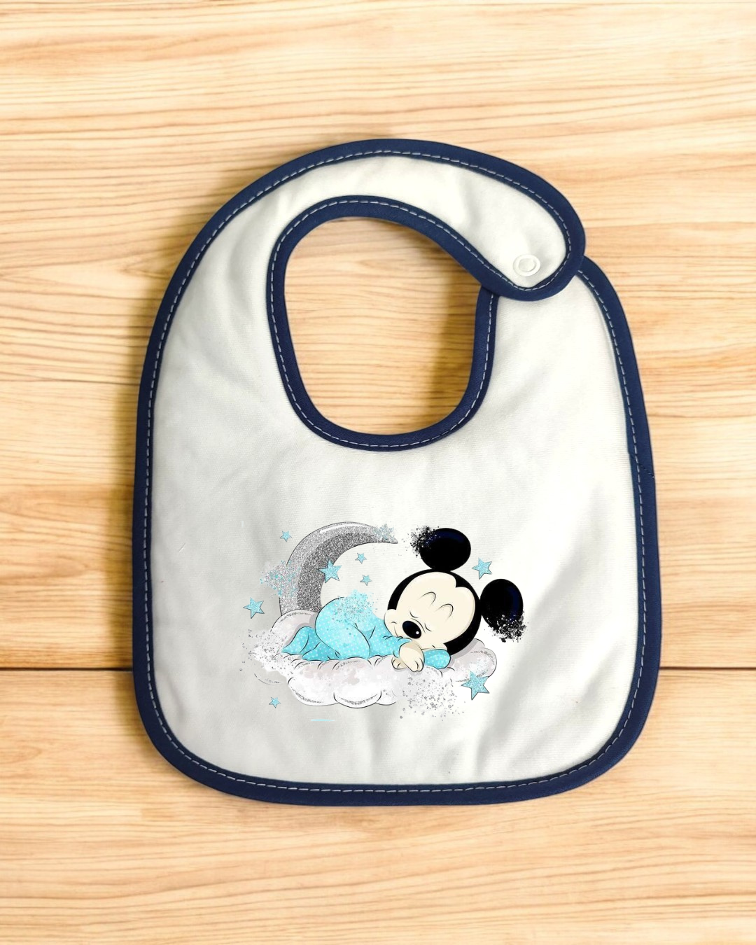 Babete azul claro com borda azul escuro e desenho do bebé Mickey Mouse numa nuvem