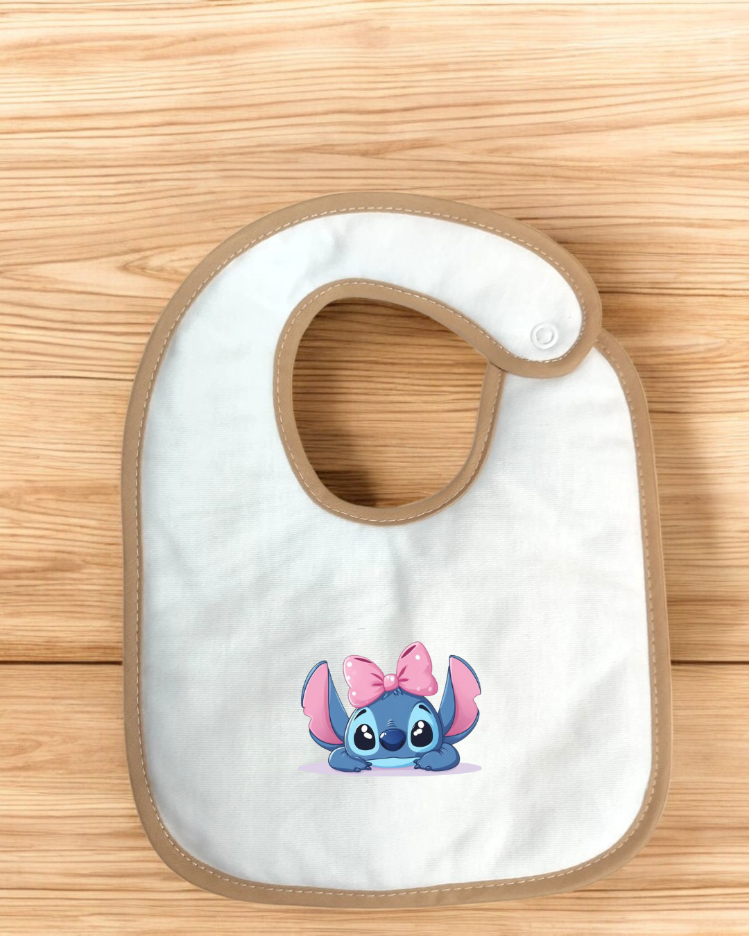 Babete branco com bordas castanho claro e personagem azul com laço cor de rosa