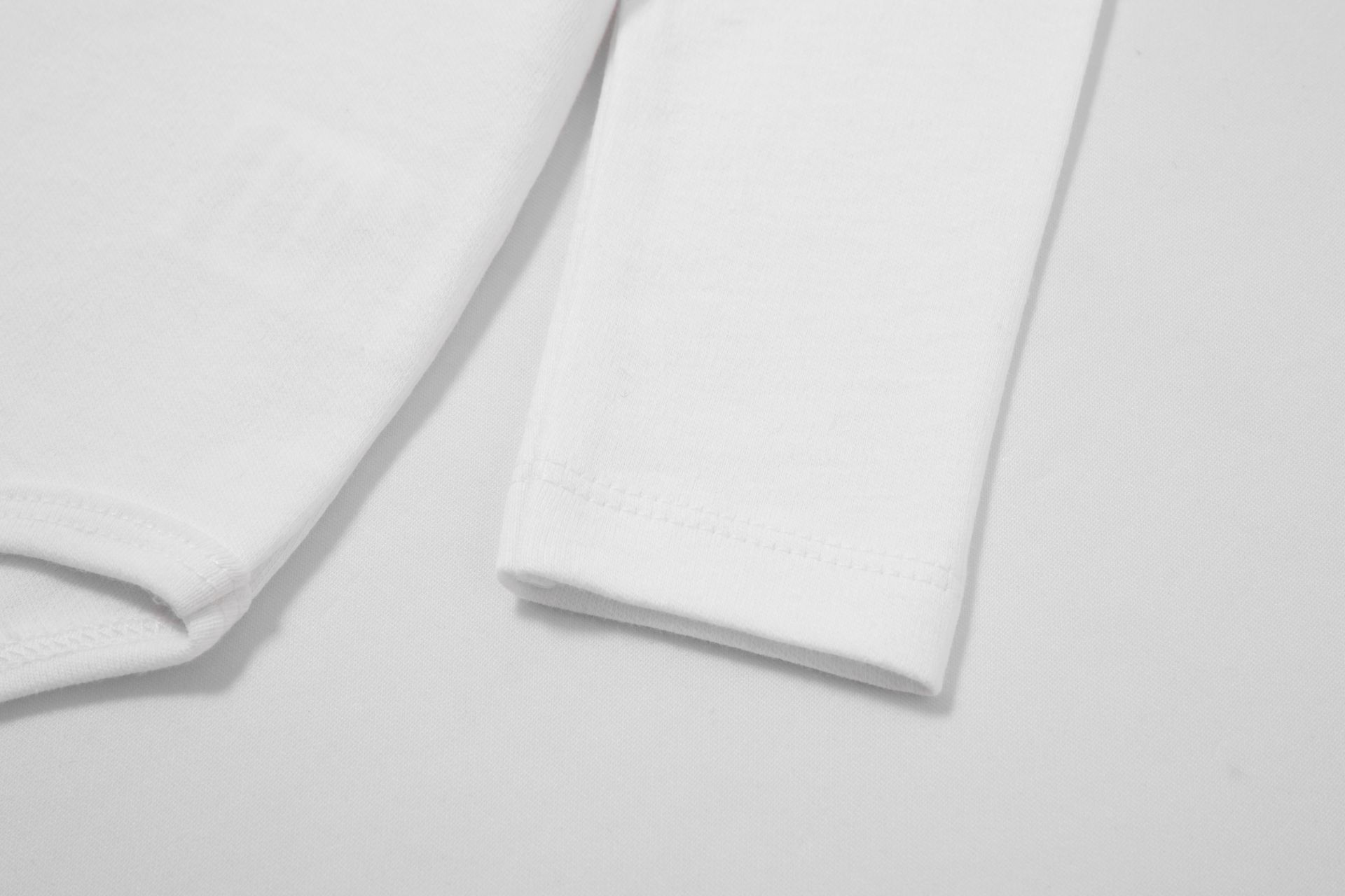 Mangas compridas de vestuário branco em tecido liso com costuras simples