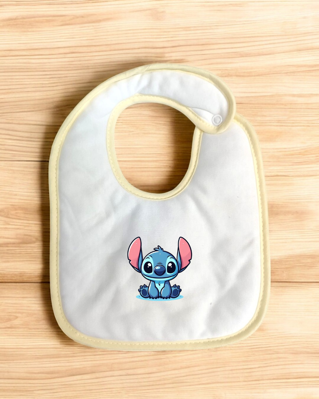 Babete branco com borda bege e ilustração do Stitch azul