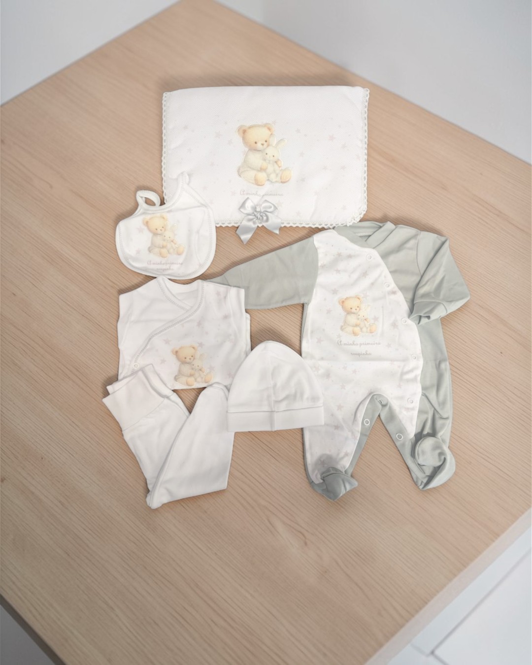 Conjunto de roupa de bebé com padrão de ursinho e coelho em tons pastel