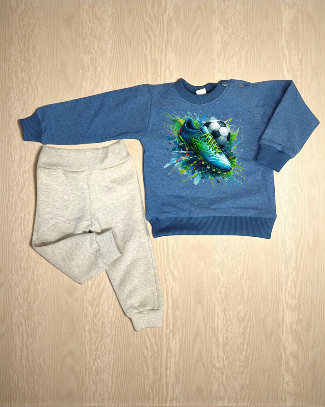 Conjunto de roupa de criança azul com chuteira e bola e calças bege