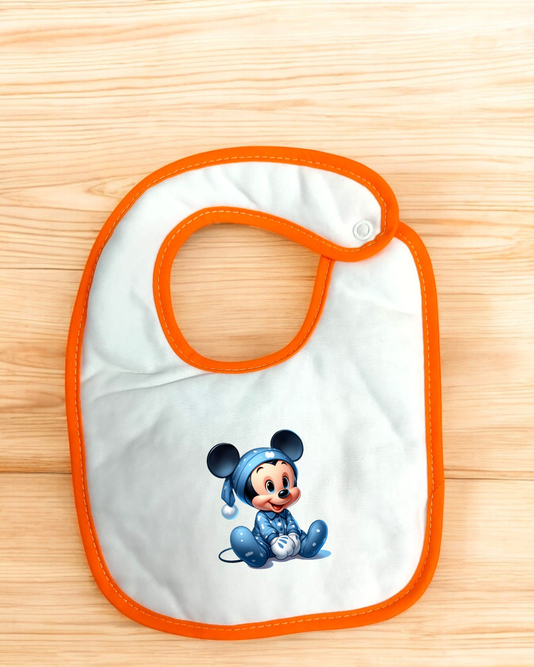 Babete branco com borda laranja e estampa de Mickey Mouse em pijama azul