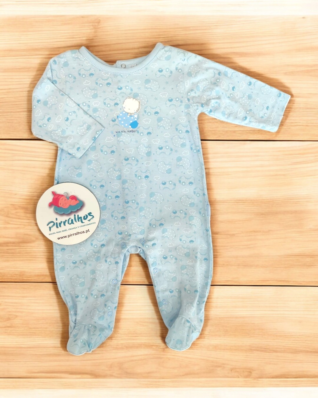 Pijama azul claro para bebé com padrão de pequenos desenhos e etiqueta redonda de tecido pirralhos