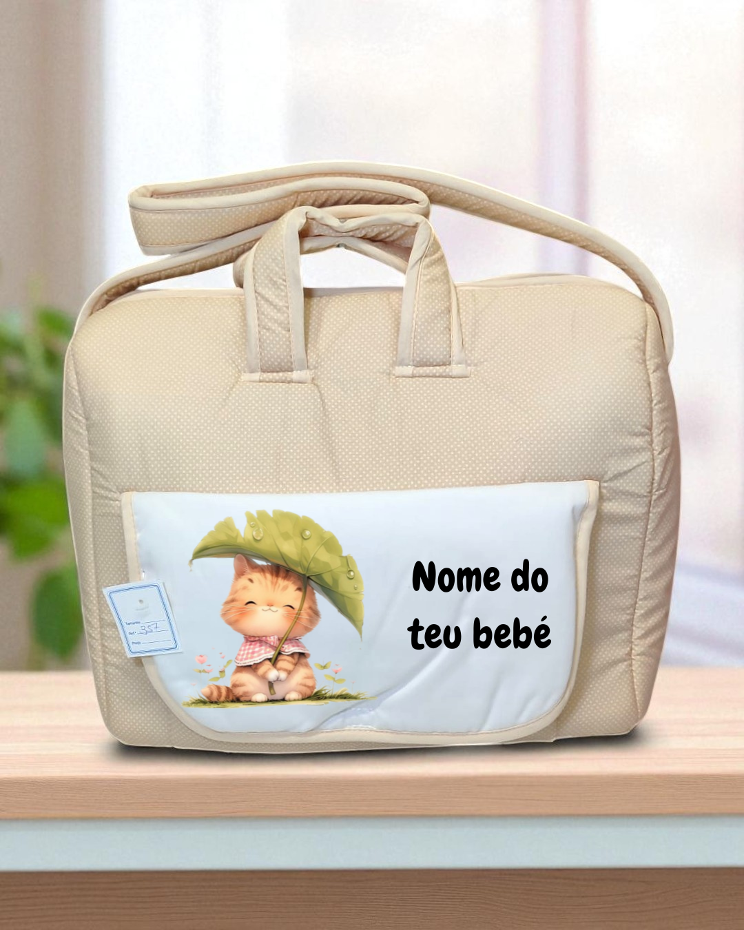 Mala de bebé bege com bolso branco e ilustração de gato e texto 'Nome do teu bebé'.