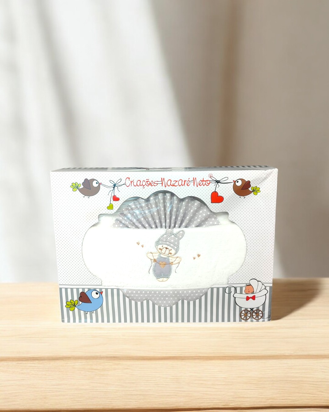 Caixa de tecido para bebé com ilustração e texto, sobre superfície de madeira
