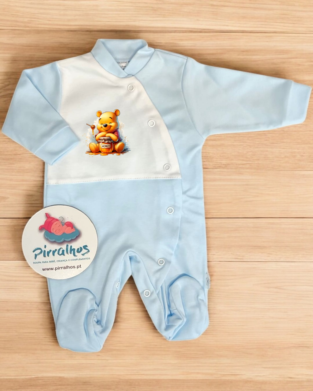 Macacão de bebé azul claro com estampa de ursinho e etiqueta da marca Pirralhos
