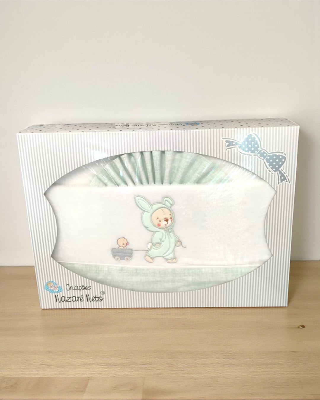Fralda de bebé branca com bordado de criança em fato de coelho e carrinho, em embalagem branca com riscas cinzentas
