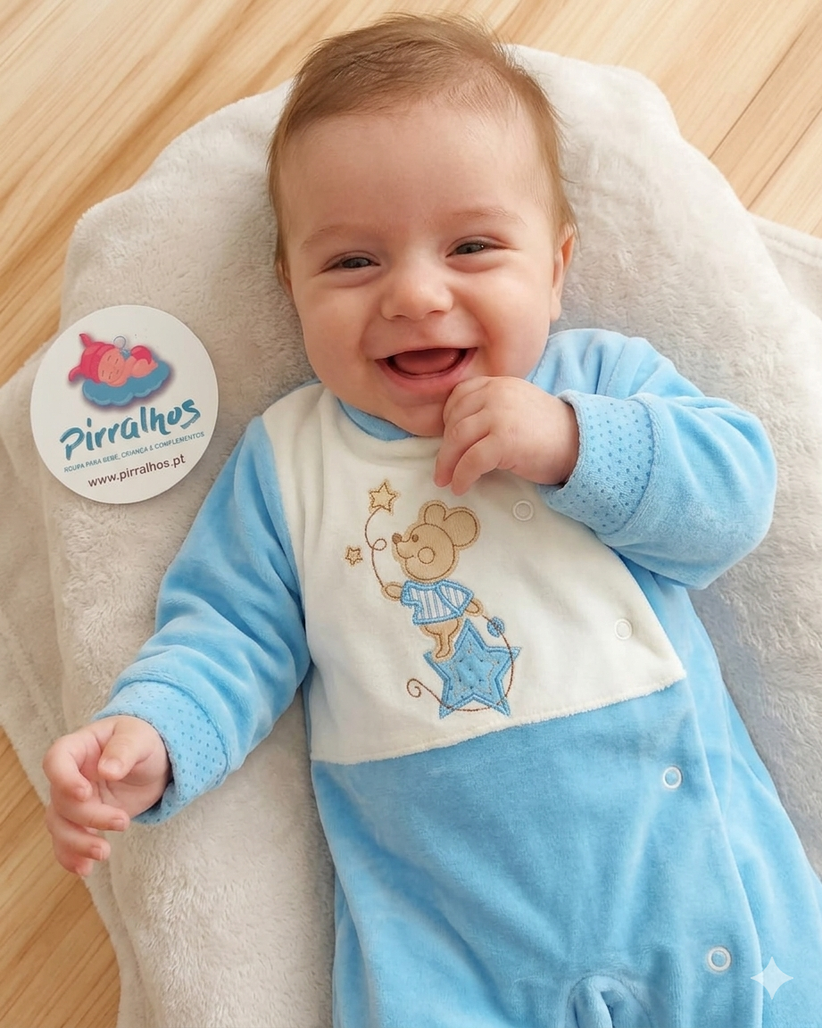 Bebé com macacão azul claro e branco deitado em almofada branca com etiqueta Pirralhos ao lado