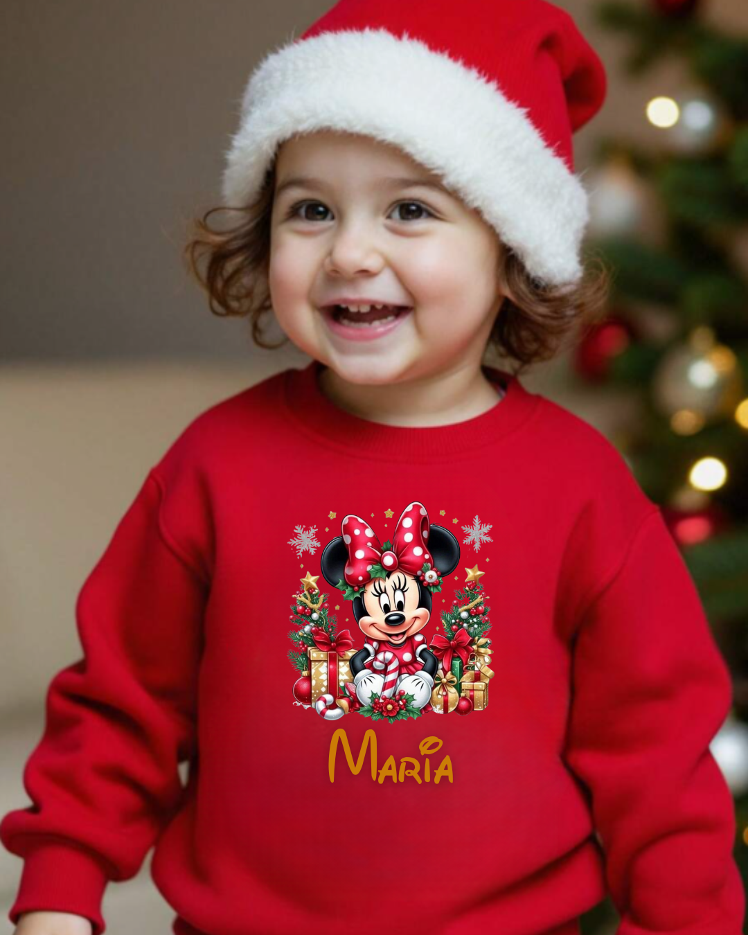 Criança vestindo sweatshirt vermelha com estampa de Minnie e nome 'MARÍA' e gorro de Natal.