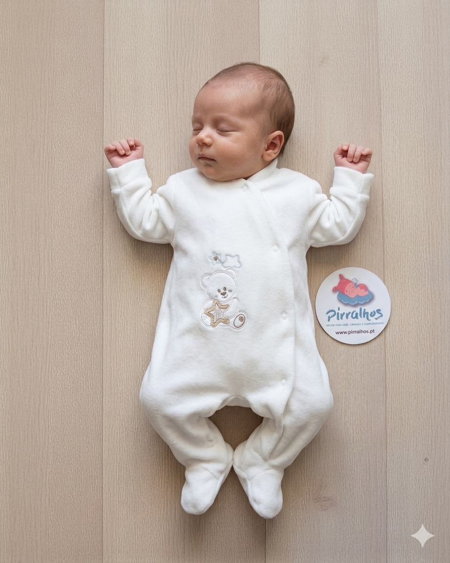 Macacão branco para bebé com ursinho bordado e estrela-do-mar, em fundo de madeira clara, com etiqueta redonda ao lado