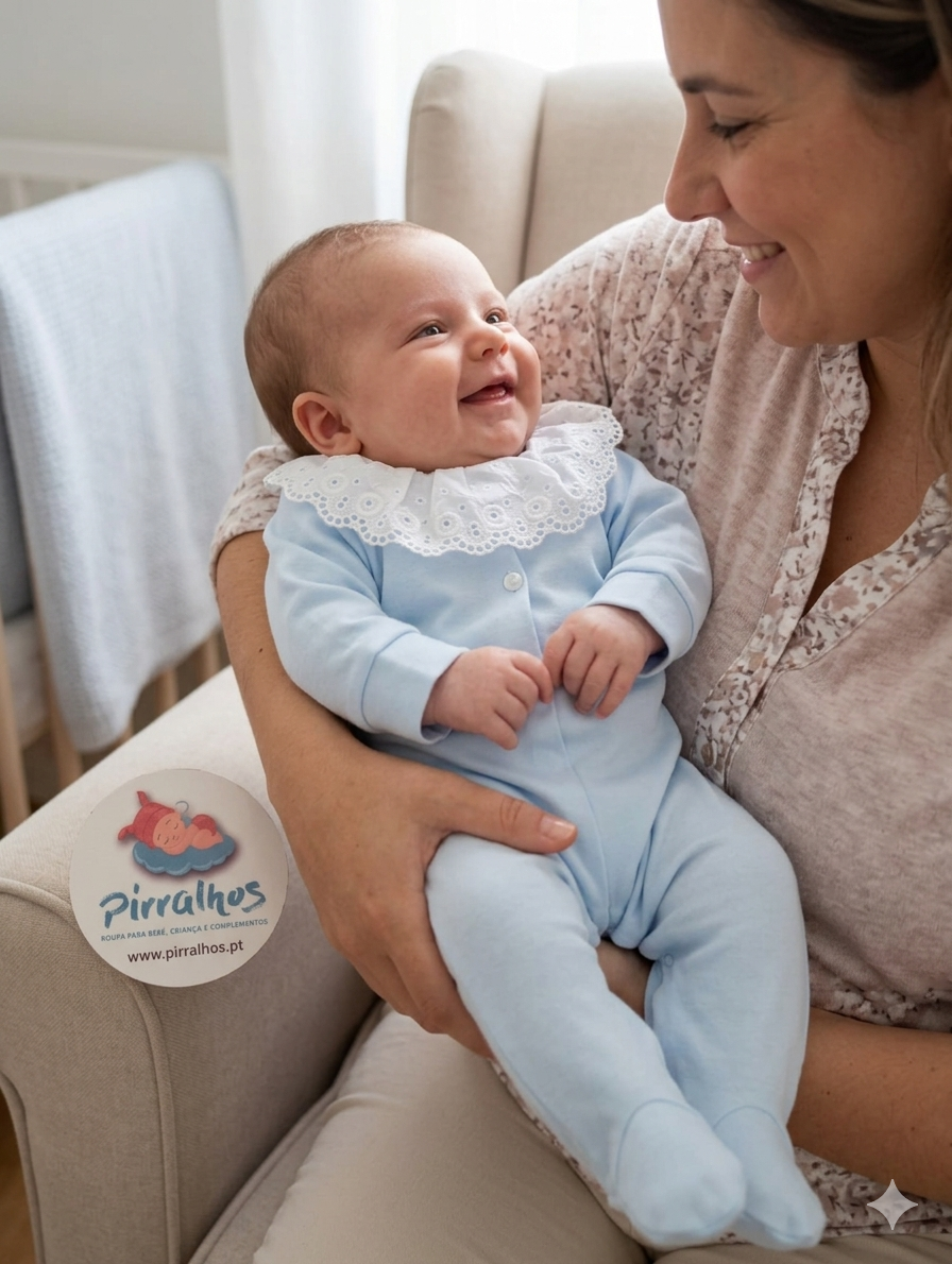 Bebé com macacão azul claro e gola branca de renda, sorrindo enquanto é segurado por mulher num sofá bege.