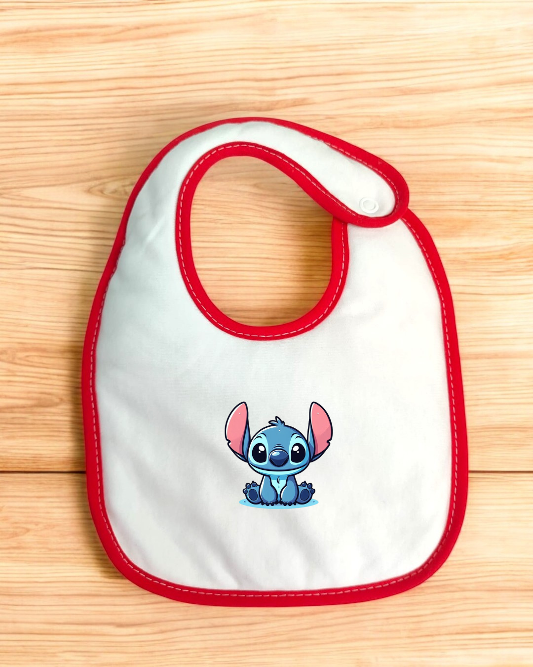 Babete branco com borda vermelha e personagem Stitch azul impresso.