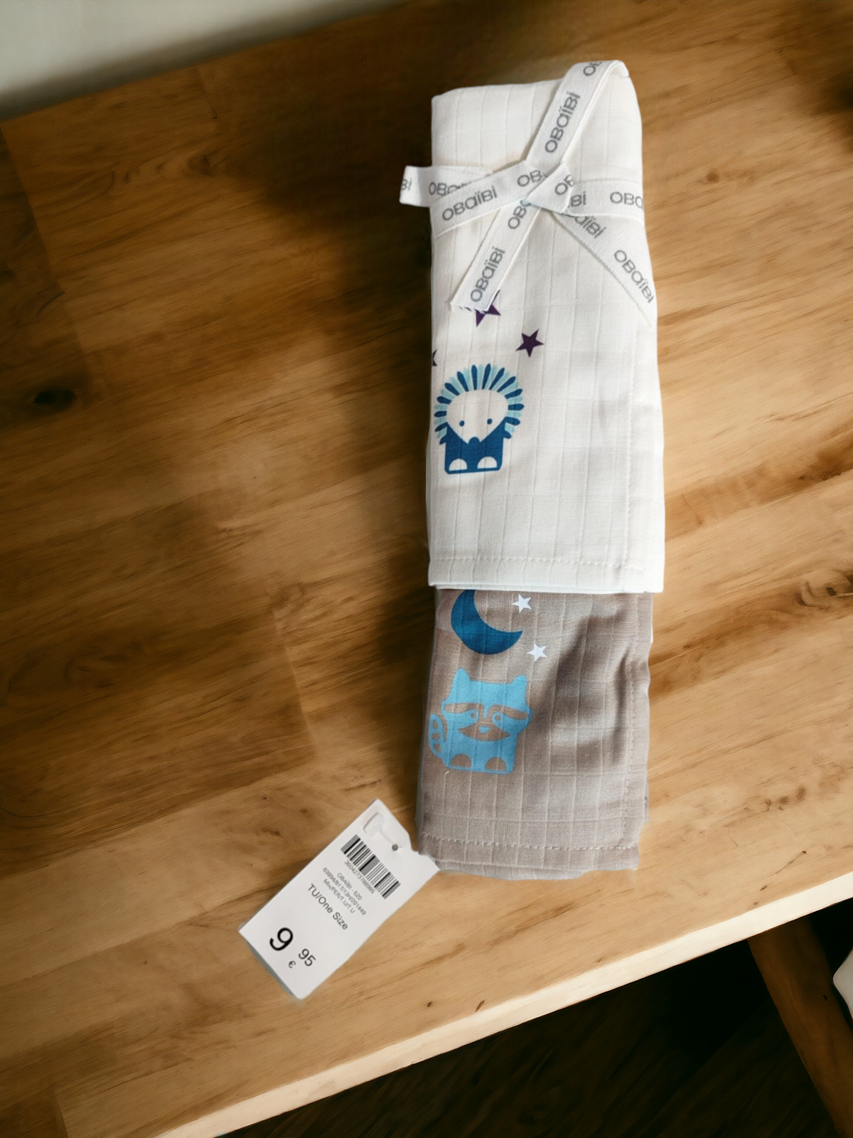 Conjunto de duas toalhas infantis dobradas com padrões azuis e etiquetas, sobre mesa de madeira.