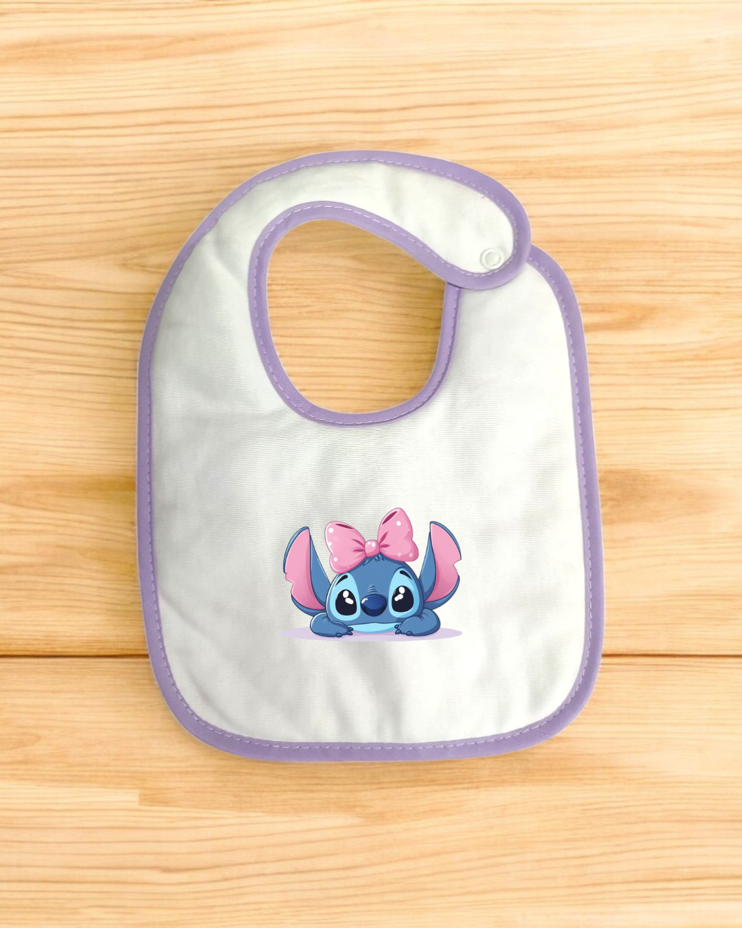Babete branco com bordas lilás e personagem azul com laço rosa