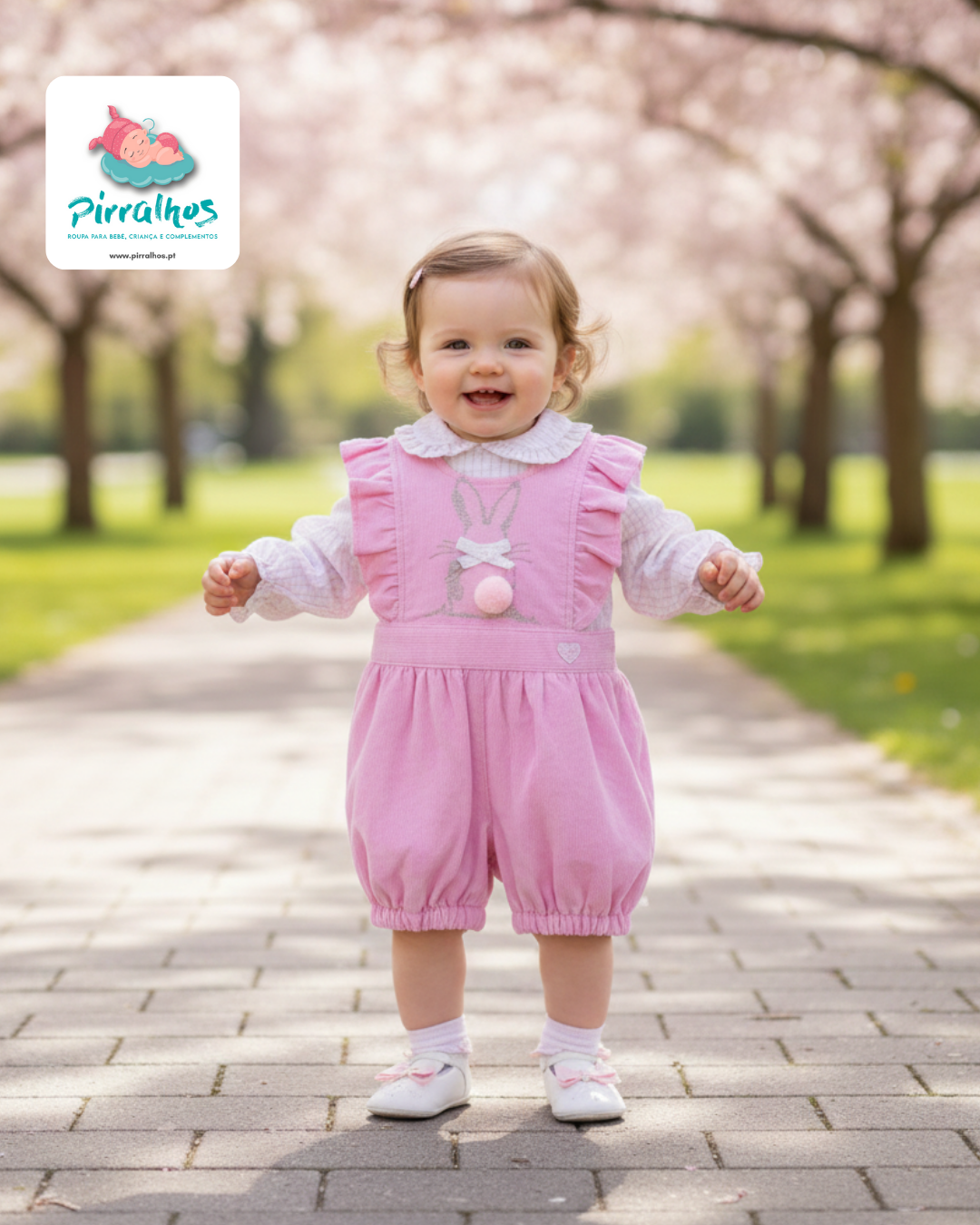 Bebé com macacão rosa e camisa branca num caminho ao ar livre