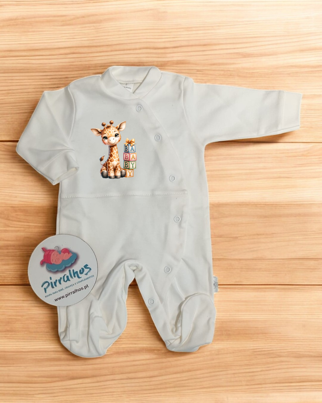 Macacão de bebé branco com estampa de girafa e blocos BABY sobre madeira clara