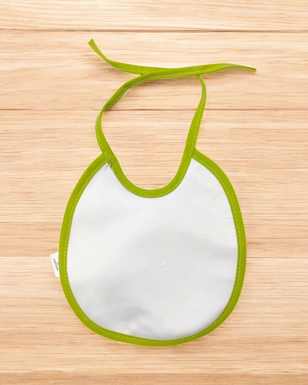 Babete branco com borda verde em superfície de madeira