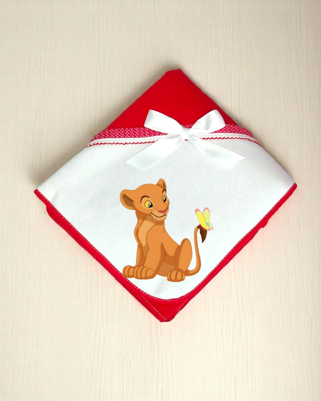 Fralda de bebé branca com bordas vermelhas e desenho de leãozinho com borboleta